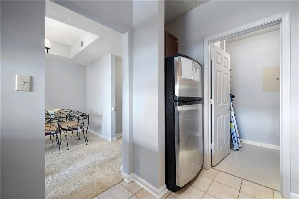 Kitchen with light colored carpet, freestanding refrigerator, a textured ceiling, and light tile patterned floors
