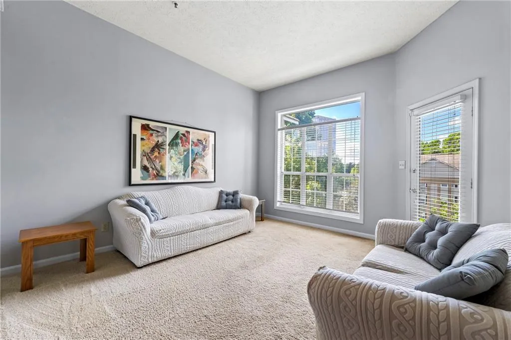 Carpeted living area with a textured ceiling and baseboards