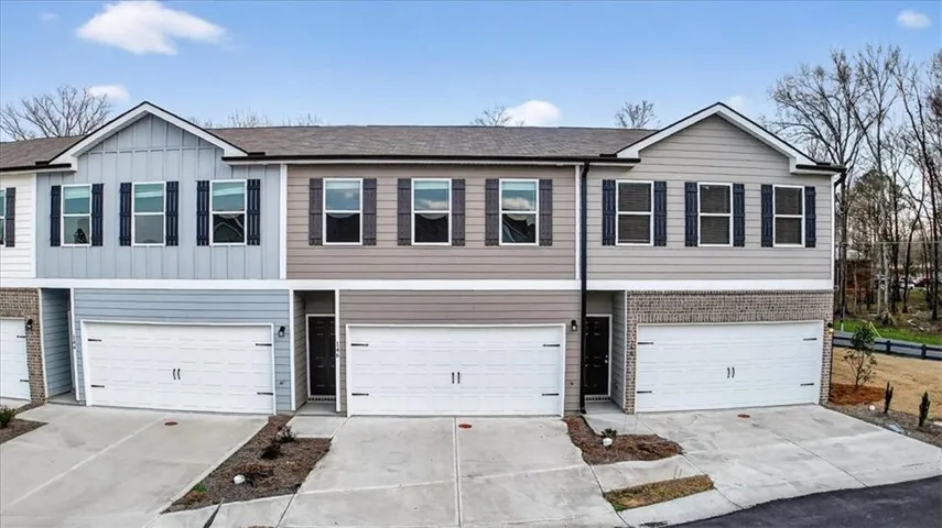 Modern townhome with attached garage, contrasting exterior finishes, dark shutters, and a covered entry