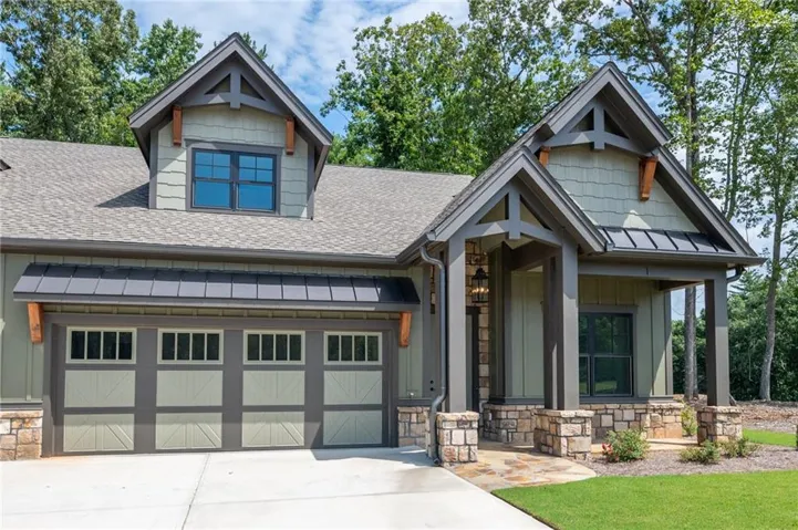 Craftsman-style exterior featuring a covered entry porch, stone accents, and a two-car garage with decorative doors