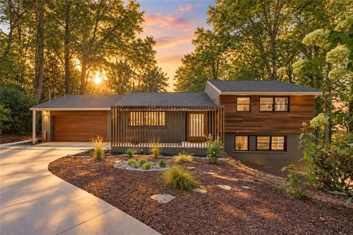 Contemporary exterior with wood-finish siding, dark framed windows, slatted wood architectural detail, integrated garage, and a landscaped front yard