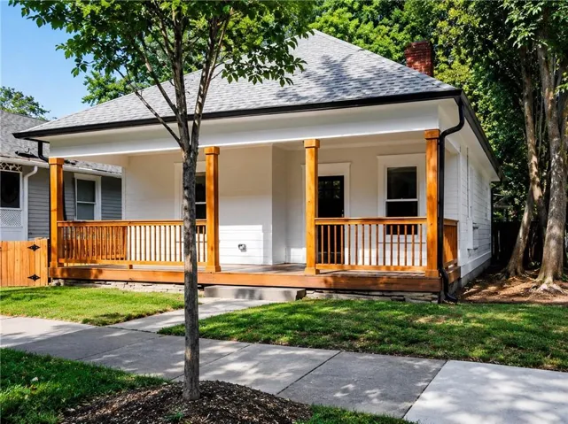 Covered front porch with wood columns and railings, white horizontal siding, and a gabled roof with dark shingles