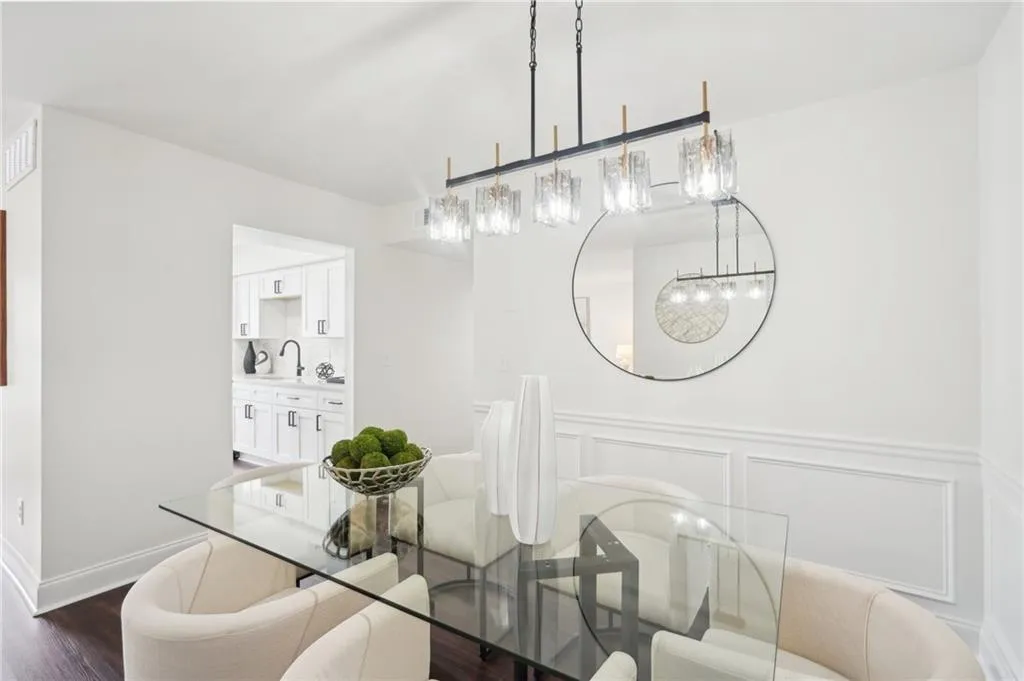 Dining space featuring a decorative wall, visible vents, a chandelier, wainscoting, and dark wood-style floors