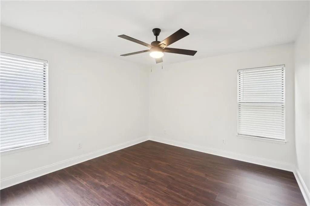Spare room featuring ceiling fan, baseboards, and dark wood finished floors