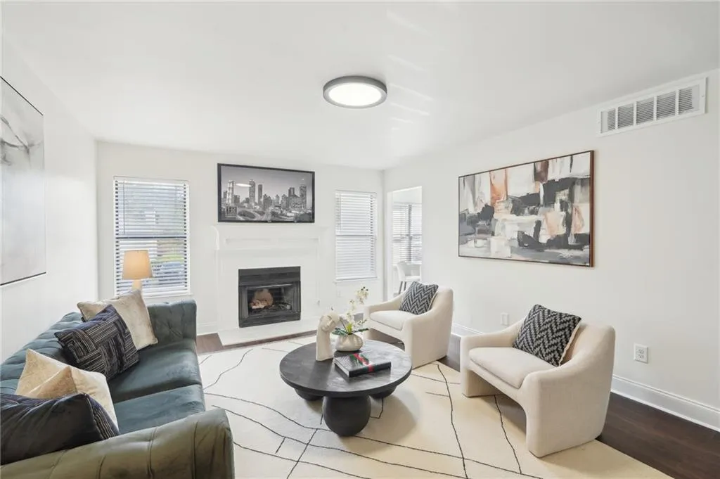 Living area featuring visible vents, wood finished floors, a glass covered fireplace, and a healthy amount of sunlight
