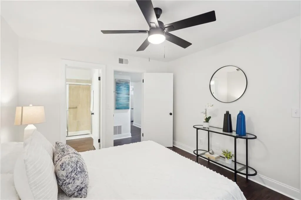 Bedroom featuring visible vents, baseboards, ensuite bath, and dark wood-style floors