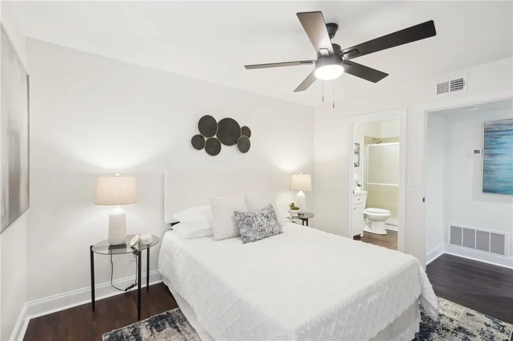Bedroom featuring wood finished floors, ensuite bathroom, baseboards, and visible vents