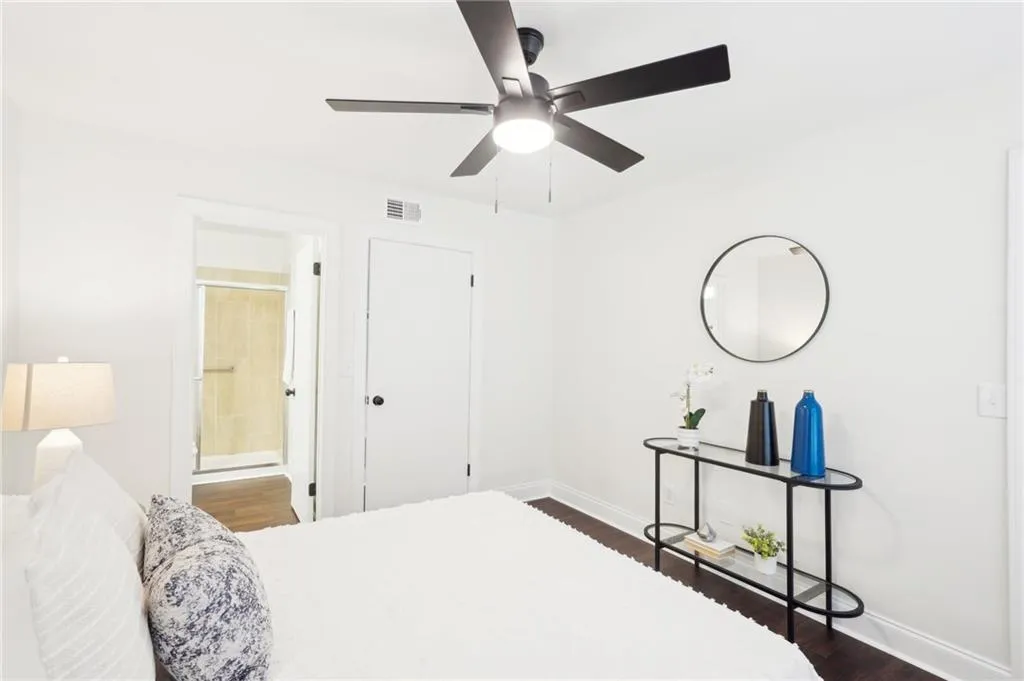 Bedroom with dark wood finished floors, connected bathroom, a ceiling fan, visible vents, and baseboards