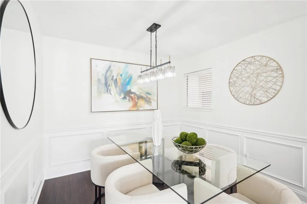 Dining space featuring a decorative wall, wainscoting, and wood finished floors