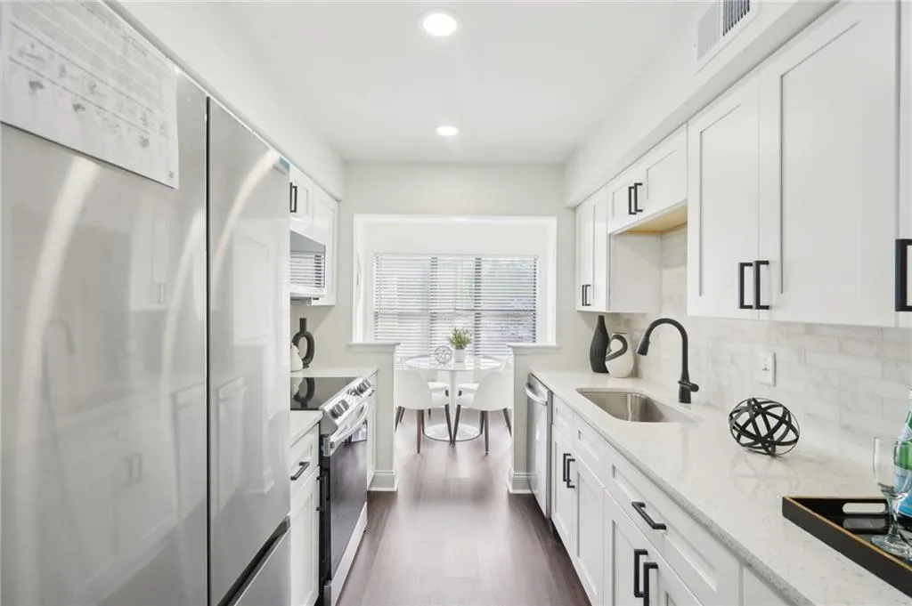 Kitchen featuring visible vents, appliances with stainless steel finishes, dark wood-style flooring, a sink, and decorative backsplash