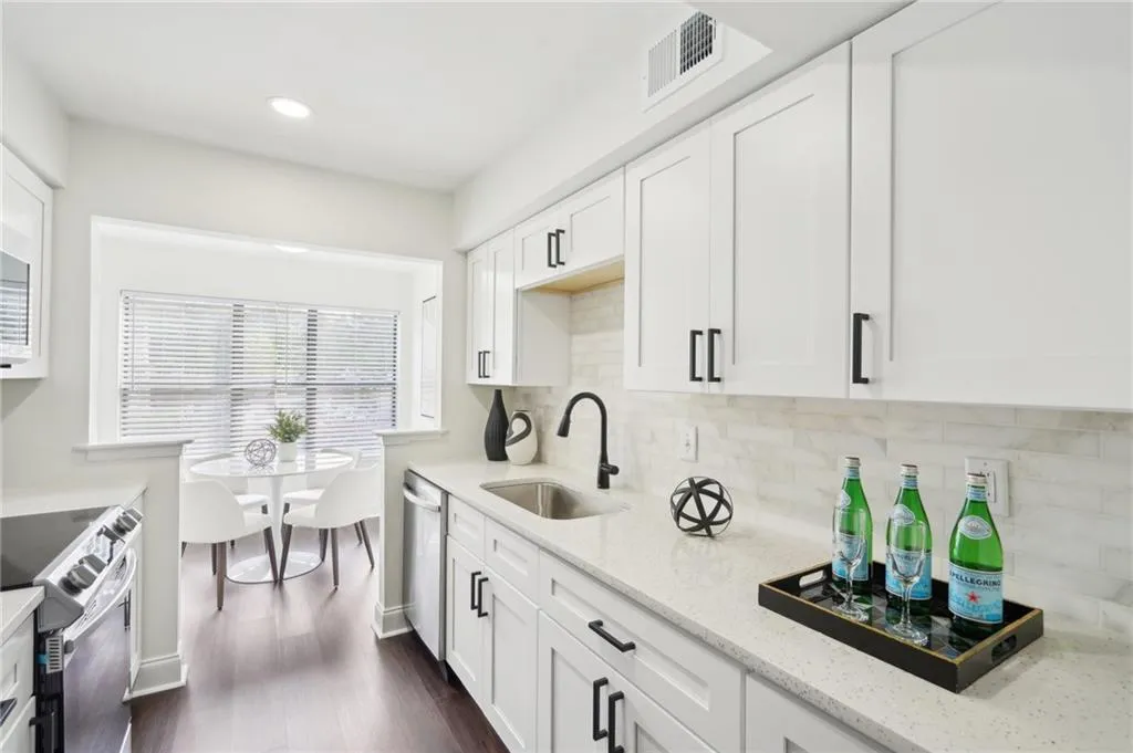 Kitchen with visible vents, a sink, appliances with stainless steel finishes, light stone countertops, and decorative backsplash