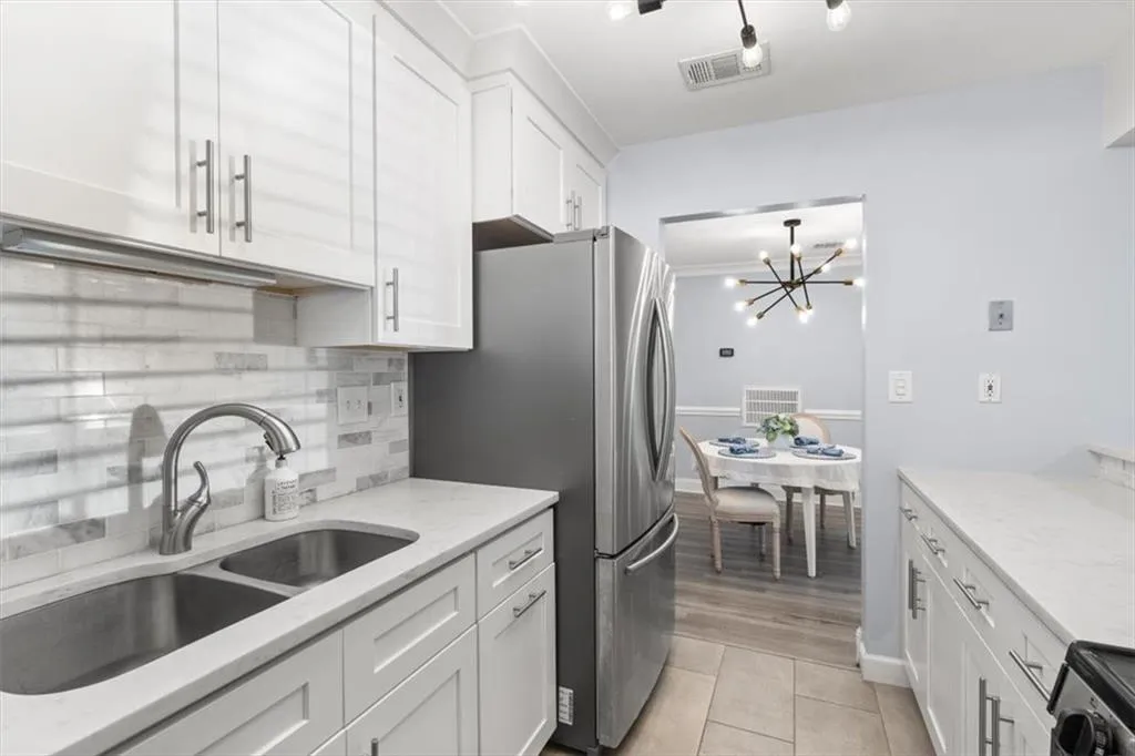 Kitchen with white cabinets, stainless gas range w/ oven, light stone countertops, and tile backsplash