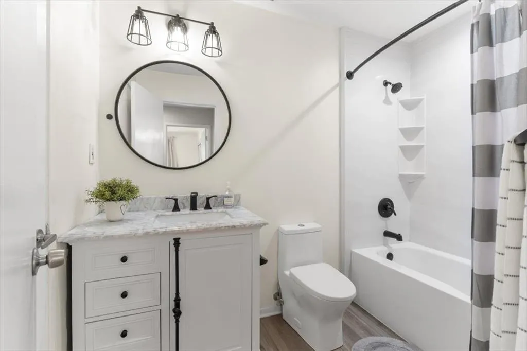 Bathroom with vanity, shower / bath combo, and wood finished floors