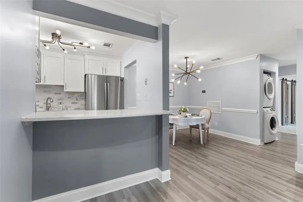 Kitchen with a chandelier, a kitchen bar, Stainless steal refrigerator, light stone countertops, and tasteful backsplash