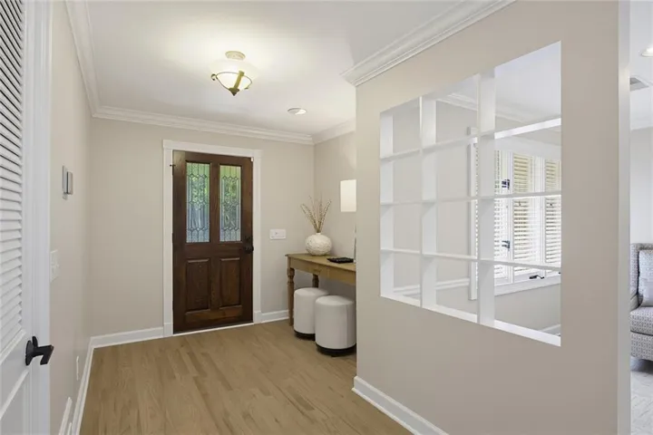 Entryway featuring wood-finish flooring, a dark wood entry door with decorative glass panels, and a built-in wall niche with shelving