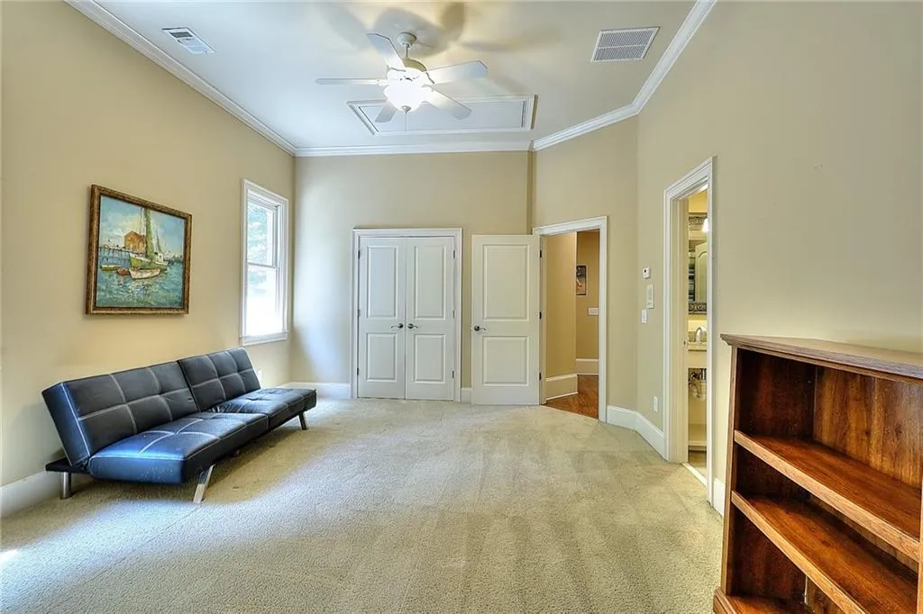 Living area featuring crown molding, light carpet, and ceiling fan