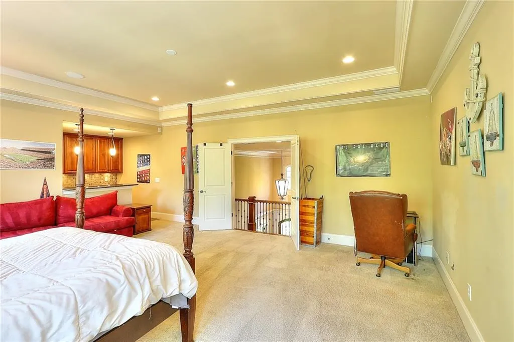 Bedroom with a raised ceiling, crown molding, and light carpet