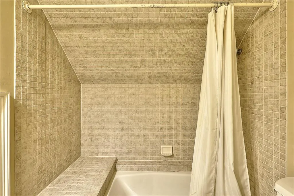 Bathroom featuring toilet, lofted ceiling, and shower / bath combo with shower curtain