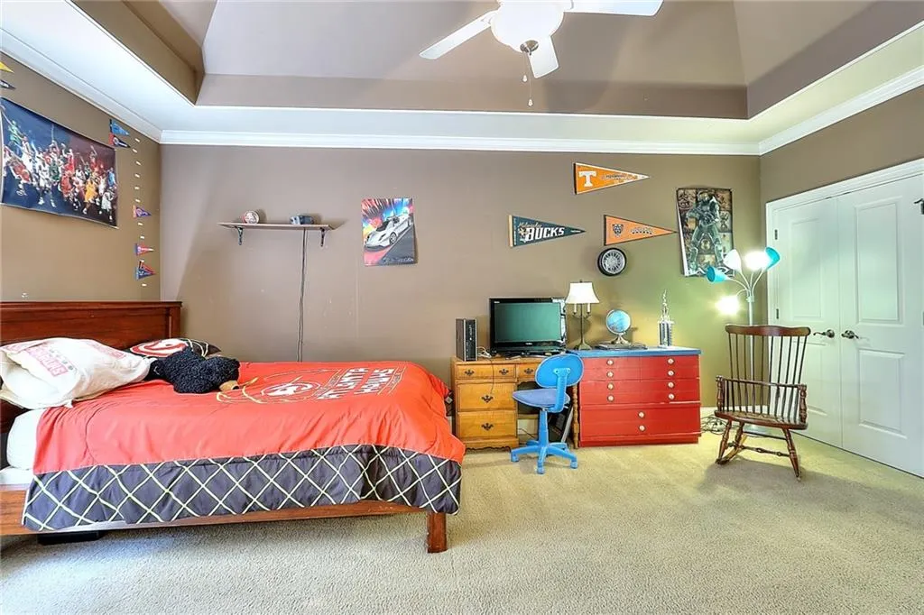 Bedroom featuring carpet floors, a tray ceiling, ceiling fan, and a closet
