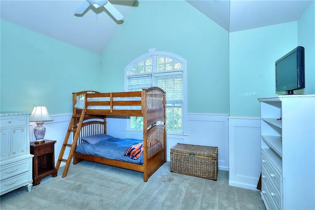 Bedroom with light carpet, vaulted ceiling, and ceiling fan