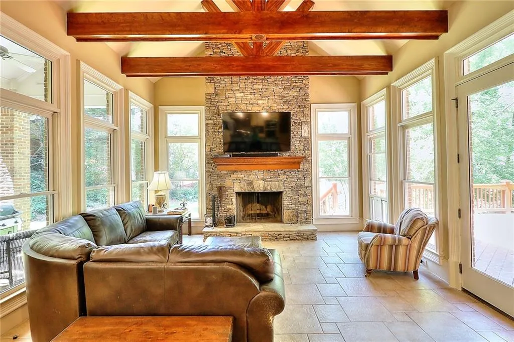 Tiled living room with ceiling fan, a fireplace, and beam ceiling
