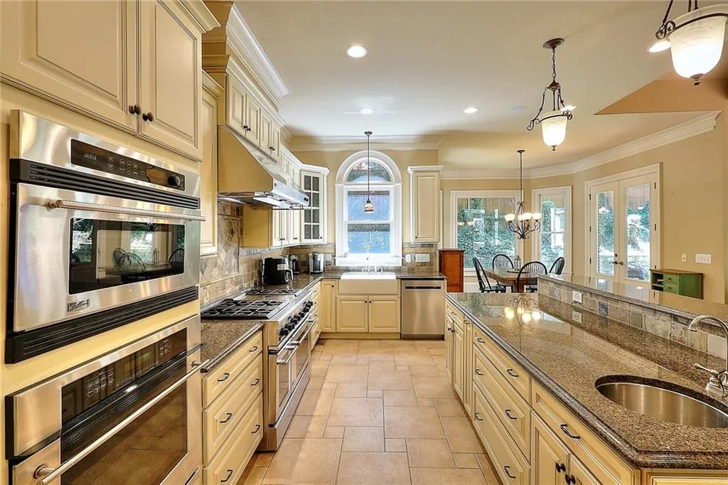 Kitchen featuring tasteful backsplash, sink, pendant lighting, a notable chandelier, and stainless steel appliances