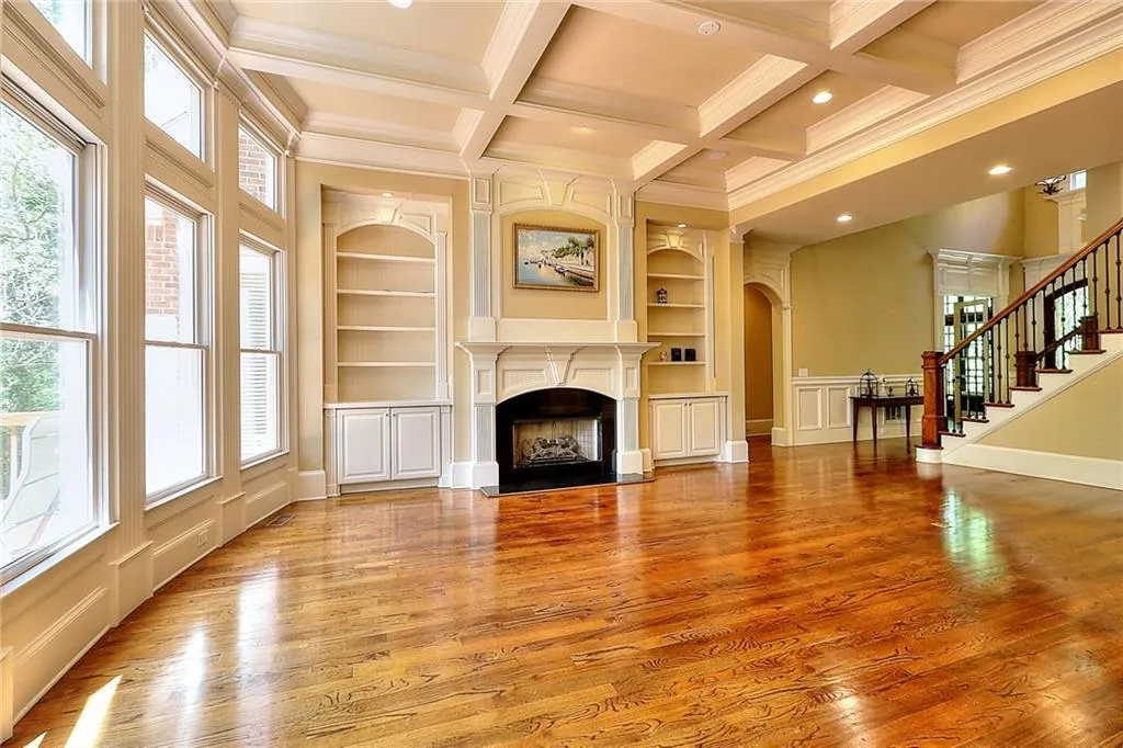 Unfurnished living room with built in features, coffered ceiling, a wealth of natural light, and light hardwood / wood-style floors