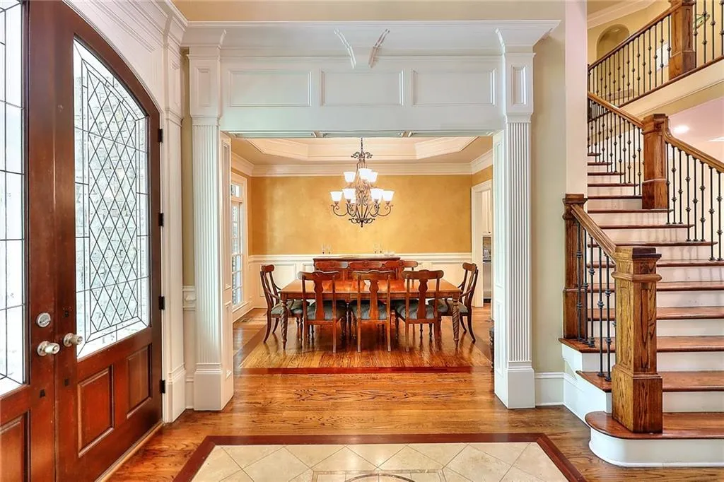 Entrance foyer with a notable chandelier, ornamental molding, hardwood / wood-style flooring, and decorative columns