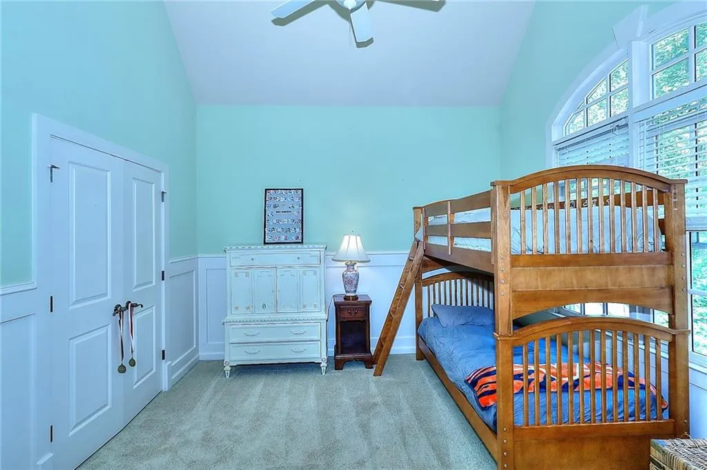 Bedroom with vaulted ceiling, light carpet, a closet, and ceiling fan