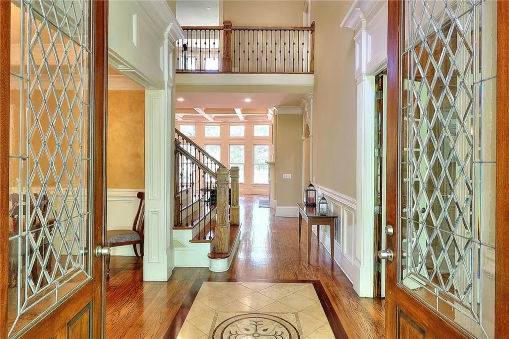 Foyer featuring ornamental molding, a towering ceiling, dark wood-type flooring, and ornate columns