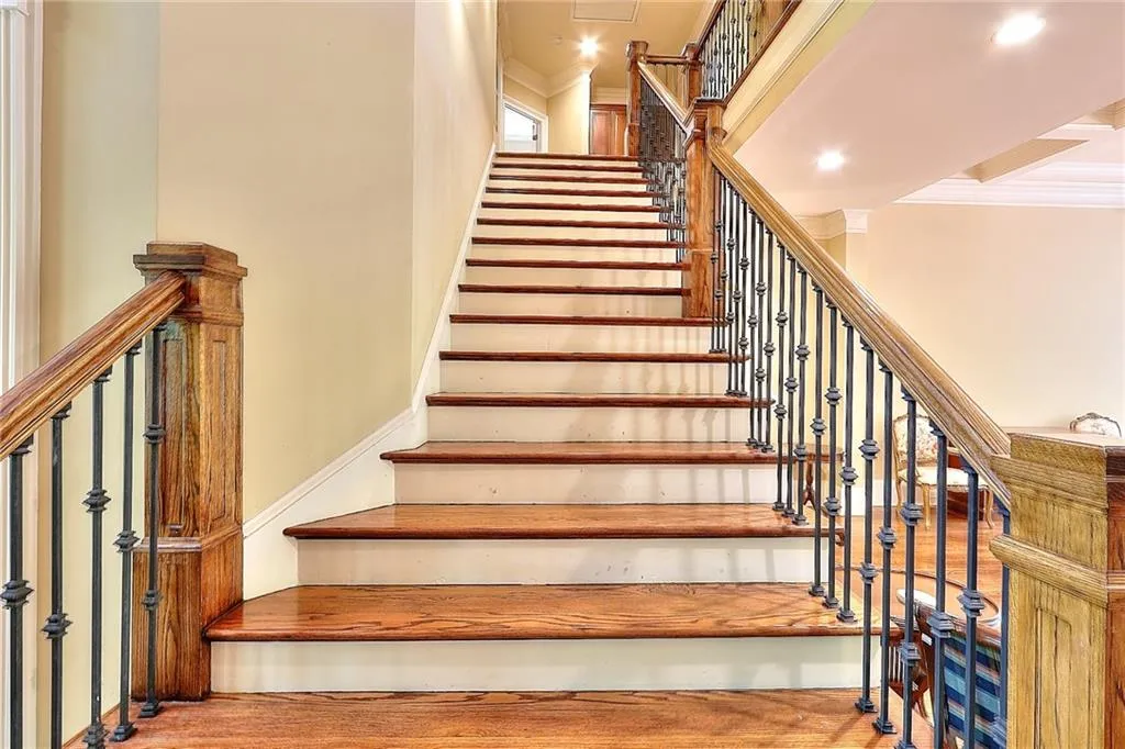 Stairway featuring light hardwood / wood-style flooring, ornamental molding, and a towering ceiling