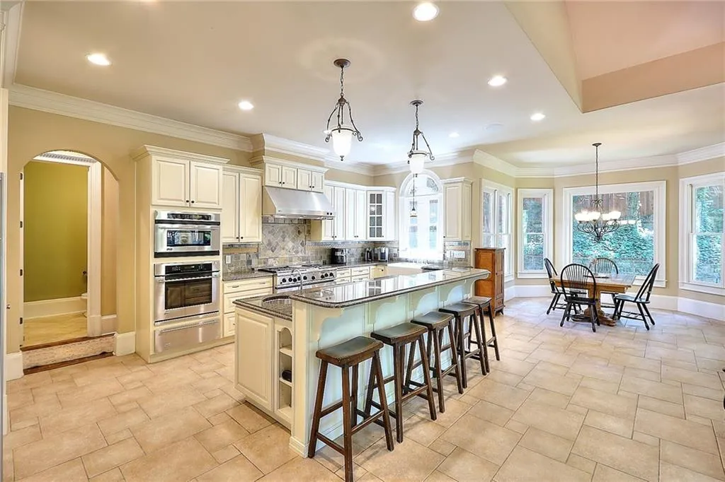 Kitchen with plenty of natural light, a chandelier, dark stone counters, a kitchen island, and stainless steel double oven