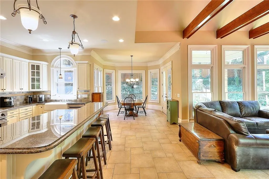 Kitchen featuring tasteful backsplash, beam ceiling, a breakfast bar, an inviting chandelier, and decorative light fixtures