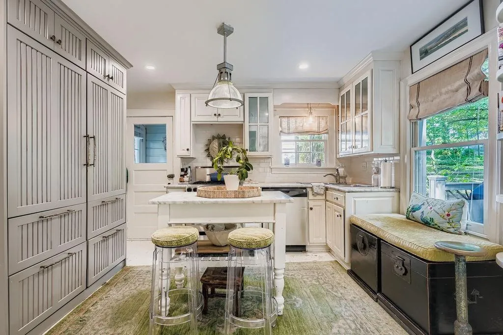 Kitchen featuring dishwasher, tasteful backsplash, glass insert cabinets, light stone counters, and decorative light fixtures