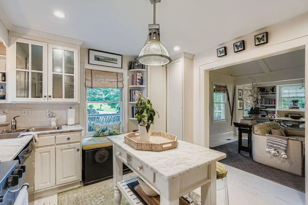 Kitchen with backsplash, glass insert cabinets, hanging light fixtures, light stone countertops, and range