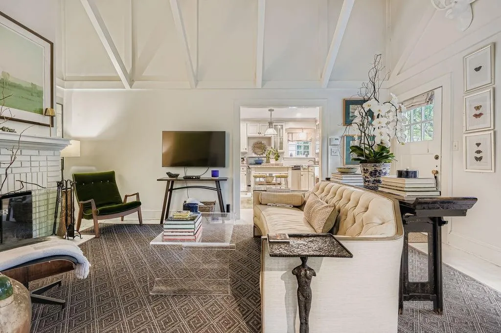 Living room featuring a brick fireplace, beam ceiling, and high vaulted ceiling