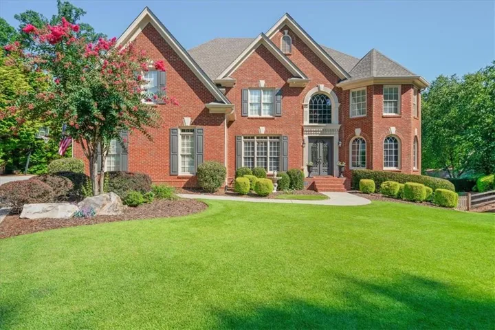 Brick exterior with architectural gables, arched windows, and a curved stone walkway