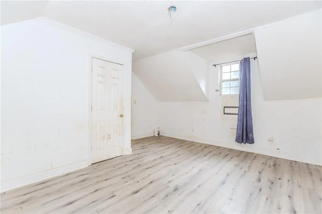 Bonus room featuring light wood-type flooring, a textured ceiling, and lofted ceiling