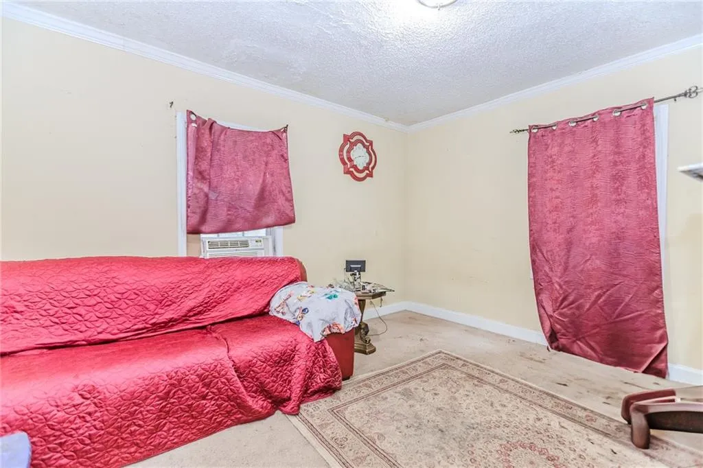 Bedroom featuring a textured ceiling, ornamental molding, and carpet floors