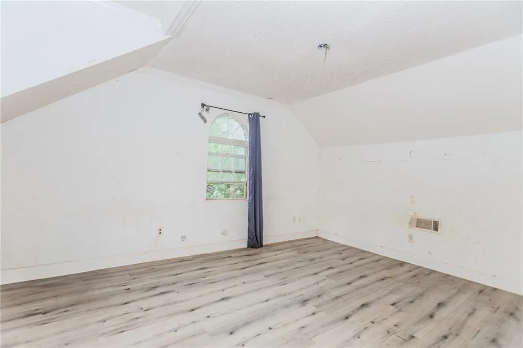 Bonus room with a textured ceiling, wood finished floors, and lofted ceiling