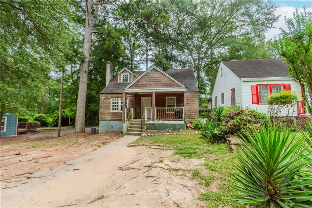 Bungalow-style house featuring covered porch, a chimney, and view of scattered trees