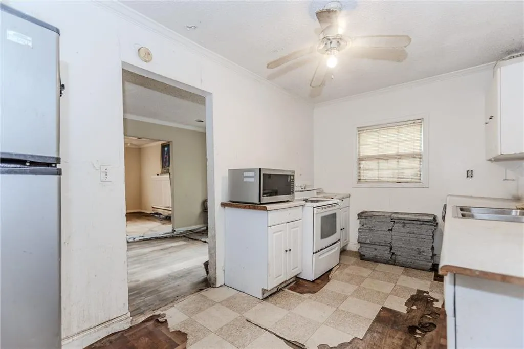 Kitchen with white cabinets, crown molding, white appliances, light countertops, and light floors