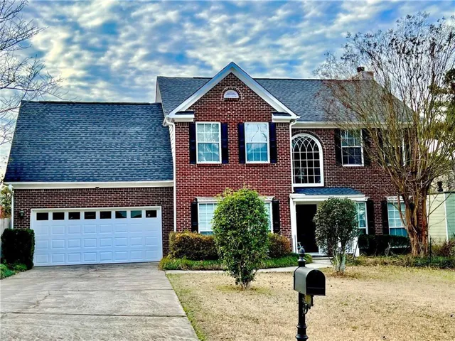 Brick exterior with a prominent arched window, a two-car garage, and a gabled roofline