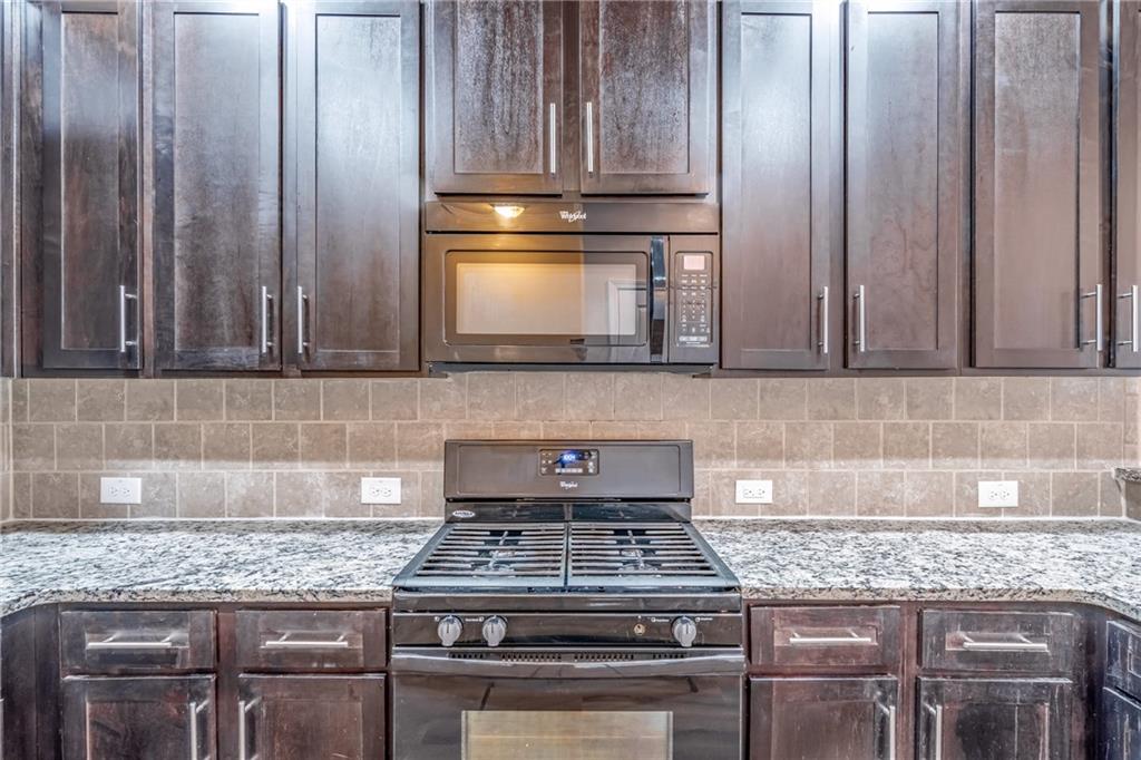 Kitchen featuring tasteful backsplash, dark brown cabinets, light stone countertops, and range Kitchen featuring tasteful backsplash, dark brown cabinets, light stone countertops, and range