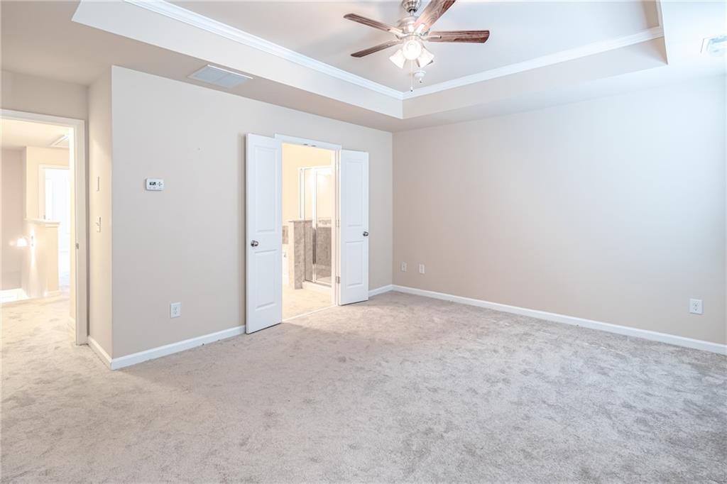 Carpeted spare room with a tray ceiling, ceiling fan, and crown molding Carpeted spare room with a tray ceiling, ceiling fan, and crown molding