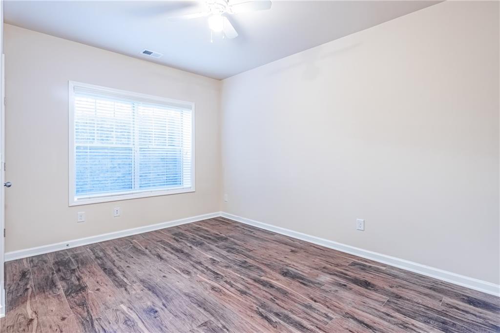 Empty room featuring ceiling fan and dark wood-type flooring Empty room featuring ceiling fan and dark wood-type flooring