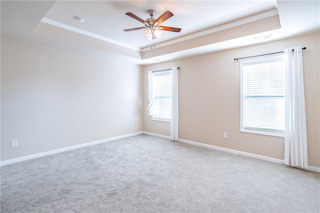 Spare room featuring light colored carpet, ceiling fan, ornamental molding, and a raised ceiling Spare room featuring light colored carpet, ceiling fan, ornamental molding, and a raised ceiling