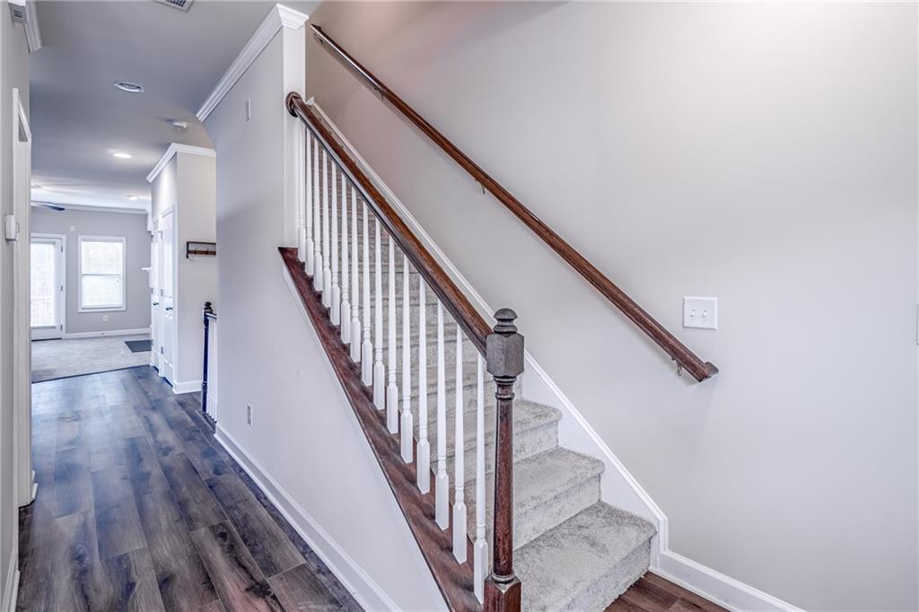 Staircase with dark wood-type flooring and crown molding Staircase with dark wood-type flooring and crown molding
