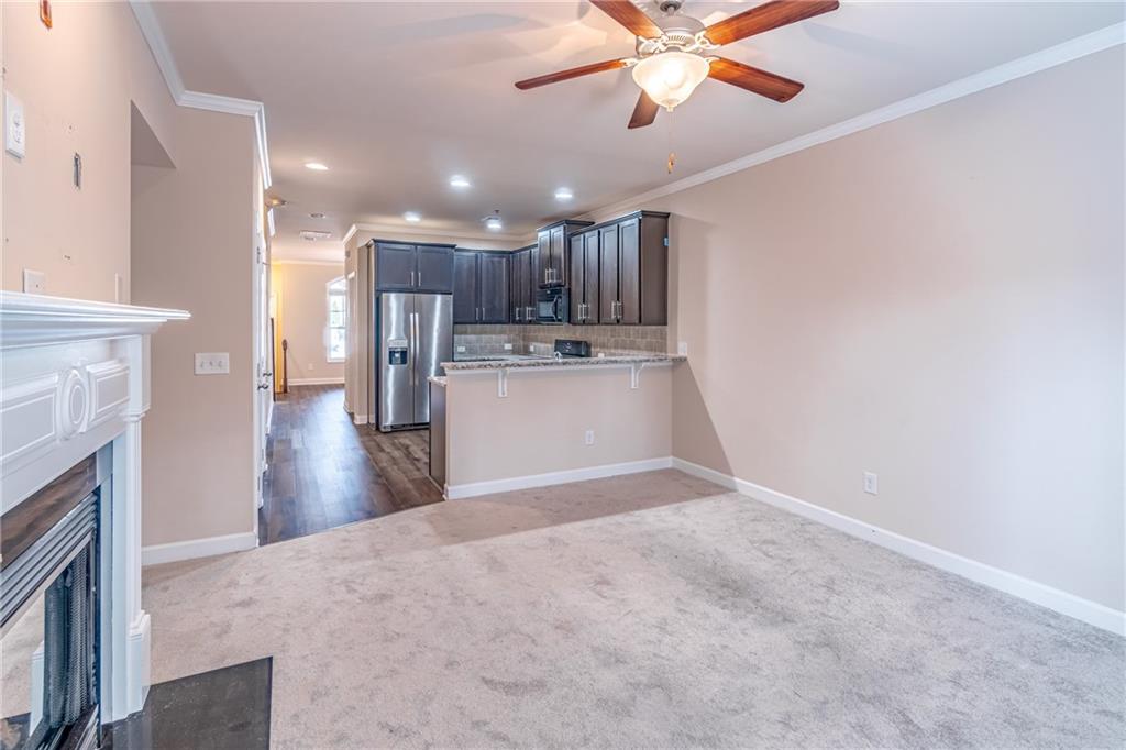 Kitchen featuring stainless steel refrigerator with ice dispenser, kitchen peninsula, ceiling fan, ornamental molding, and tasteful backsplash Kitchen featuring stainless steel refrigerator with ice dispenser, kitchen peninsula, ceiling fan, ornamental molding, and tasteful backsplash