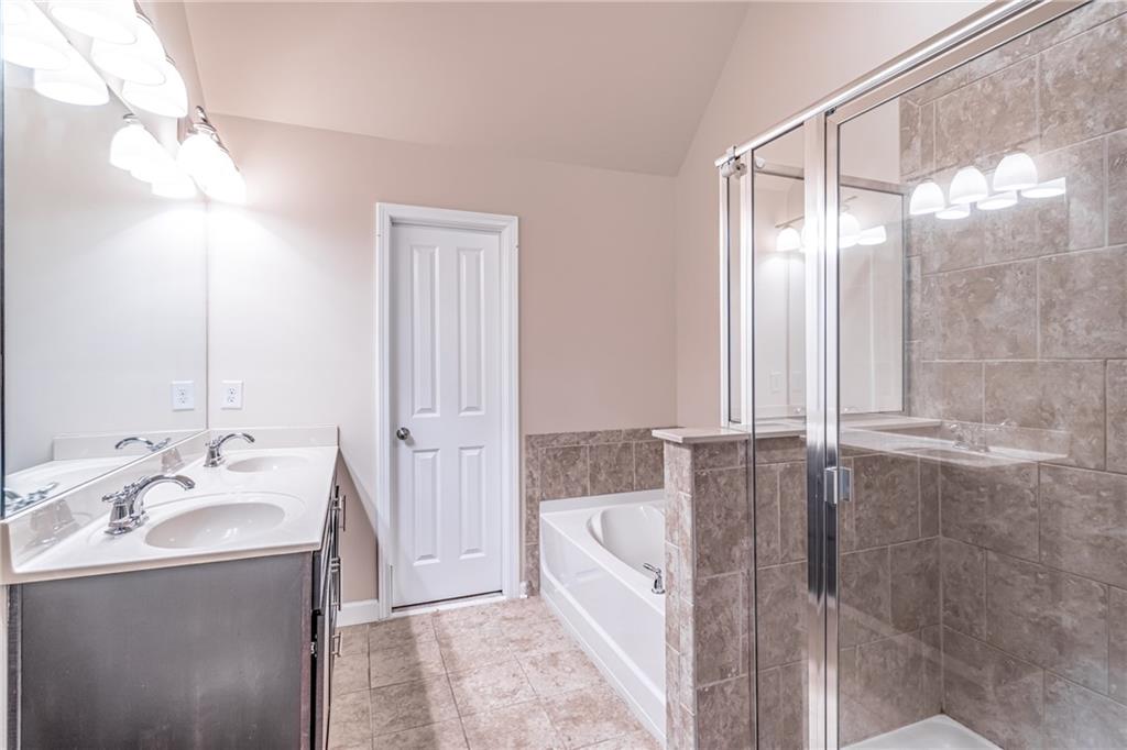 Bathroom featuring lofted ceiling, independent shower and bath, tile flooring, and dual bowl vanity Bathroom featuring lofted ceiling, independent shower and bath, tile flooring, and dual bowl vanity